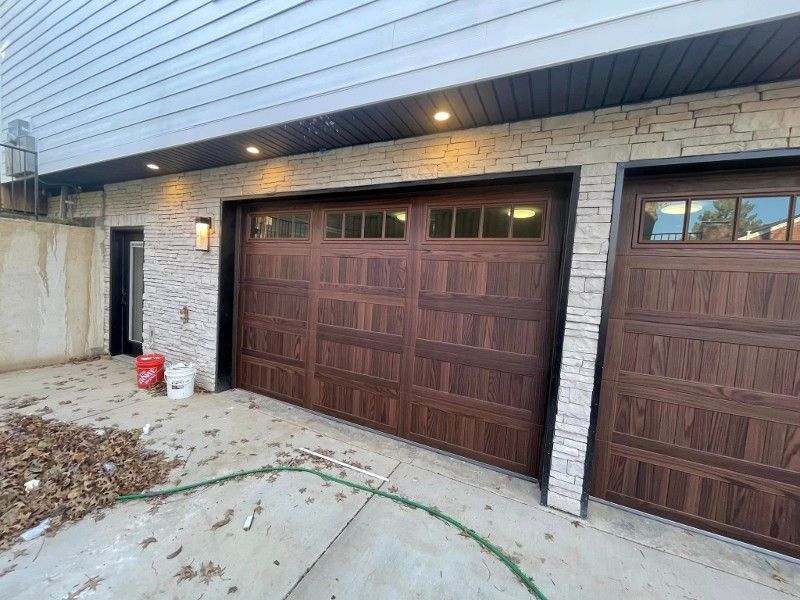 A house with two garage doors and a hose in front of it.