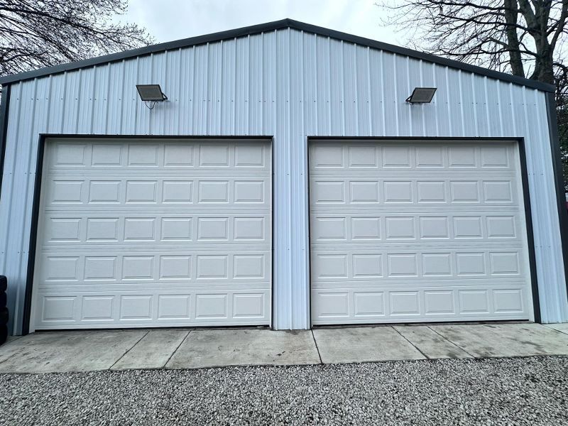 A white garage with two white garage doors and a black roof.
