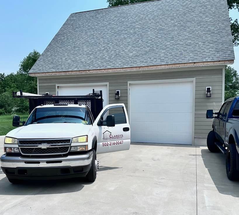 A white truck with the door open is parked in front of a garage.