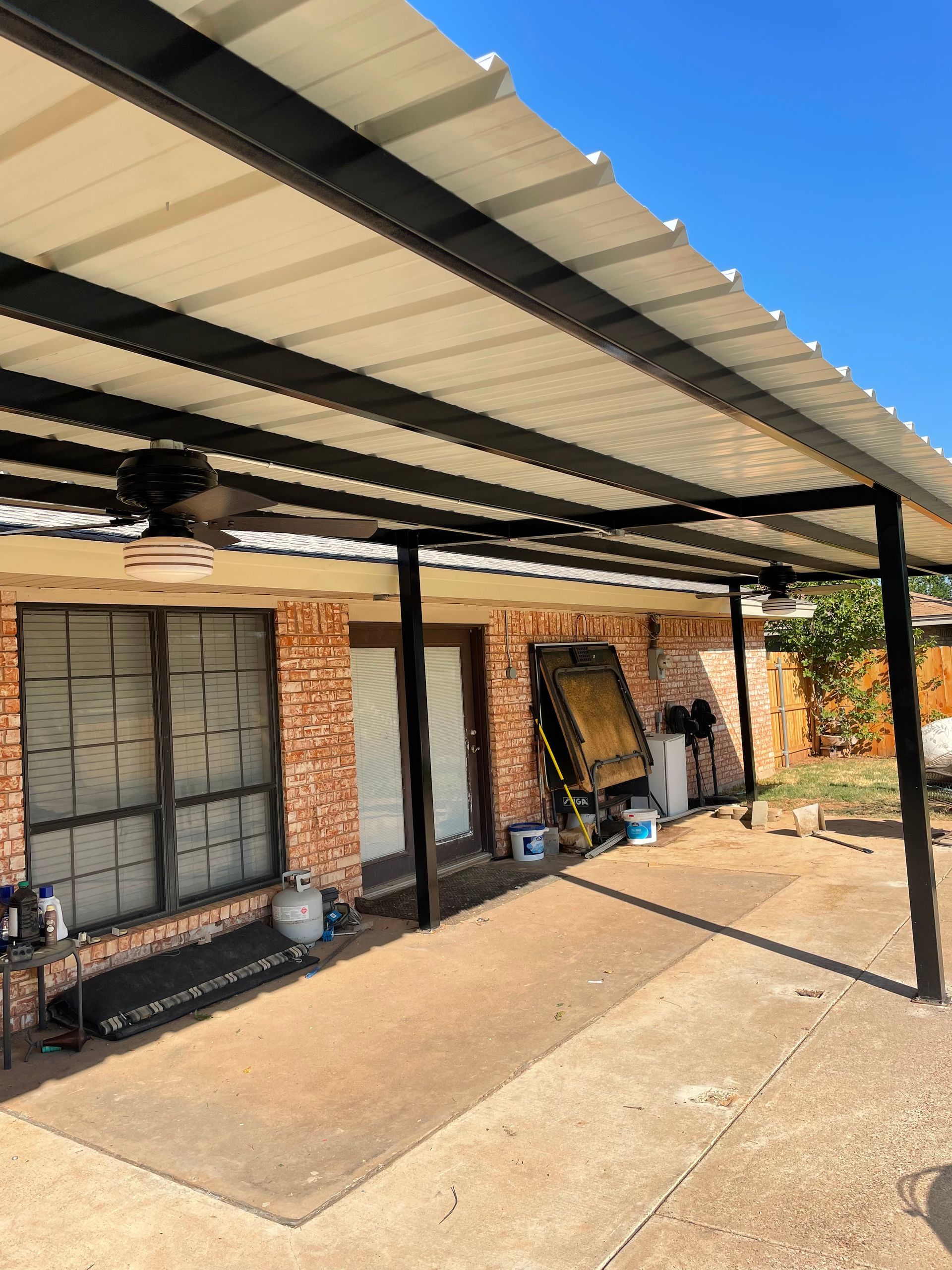 Covered patio with metal roof, black beams, and brick exterior.