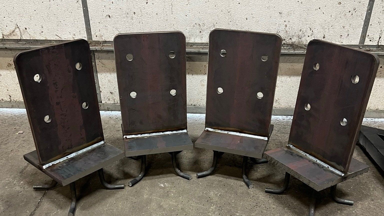 Four welded metal brackets, each with a vertical plate and horizontal base.