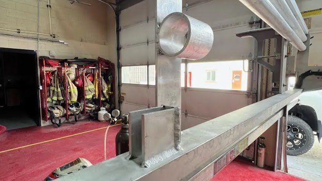 Metal fabrication in a fire station with a red floor. Fire gear hangs on the left.