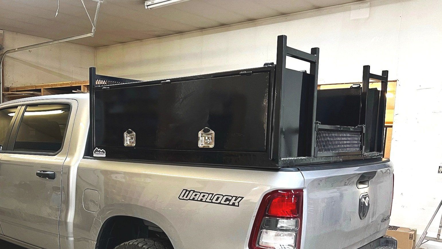 Silver pickup truck with black toolboxes and ladder racks.