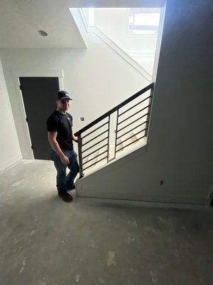 Person standing near a staircase with metal railing in a room under construction.