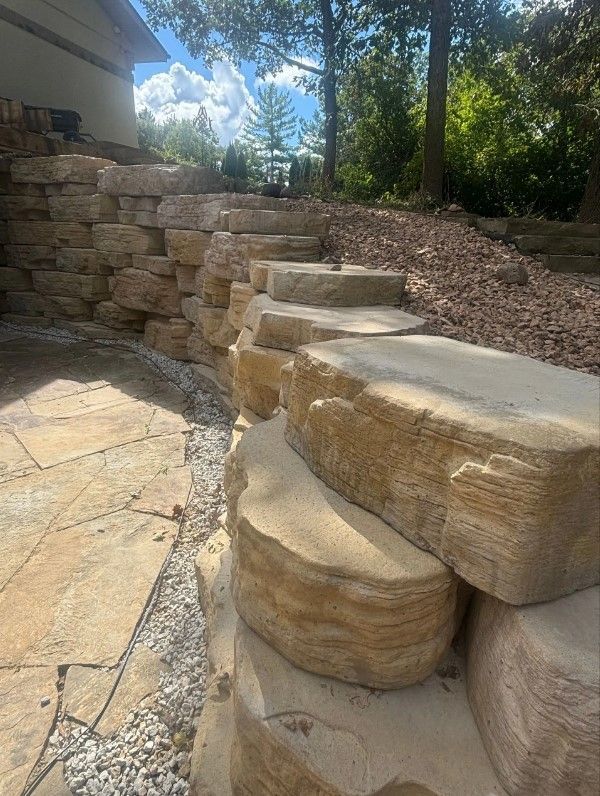 A stone wall with steps leading up to a house.