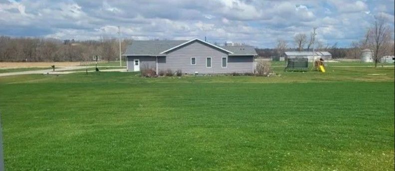 A house is sitting in the middle of a lush green field.