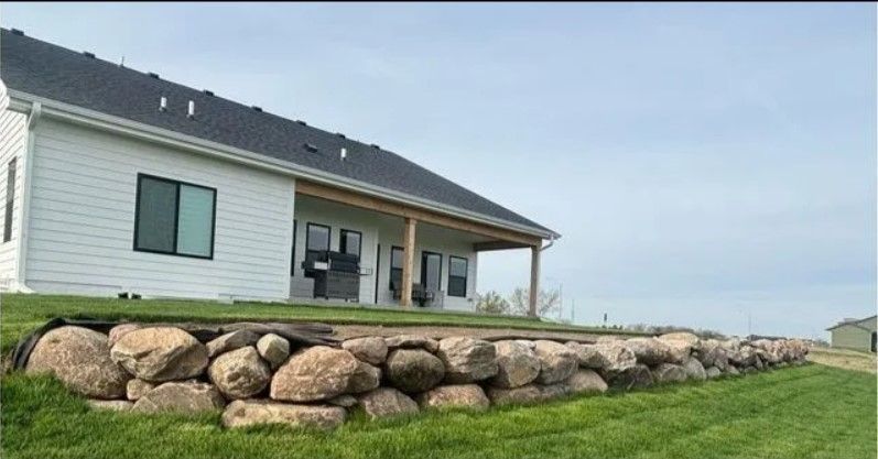 A white house with a stone wall in front of it.