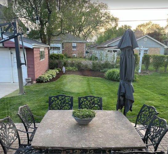 A table with chairs and an umbrella in a backyard