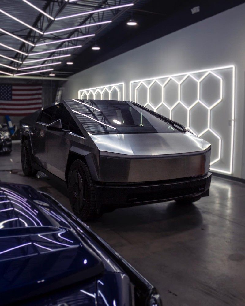 A silver car is parked next to a blue car in a showroom