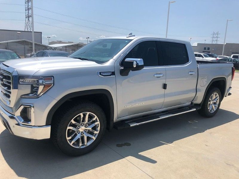 A silver gmc sierra pickup truck is parked in a parking lot.