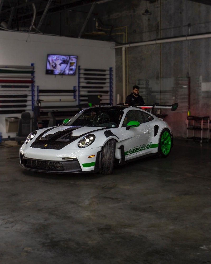A white and green sports car is parked in a garage.
