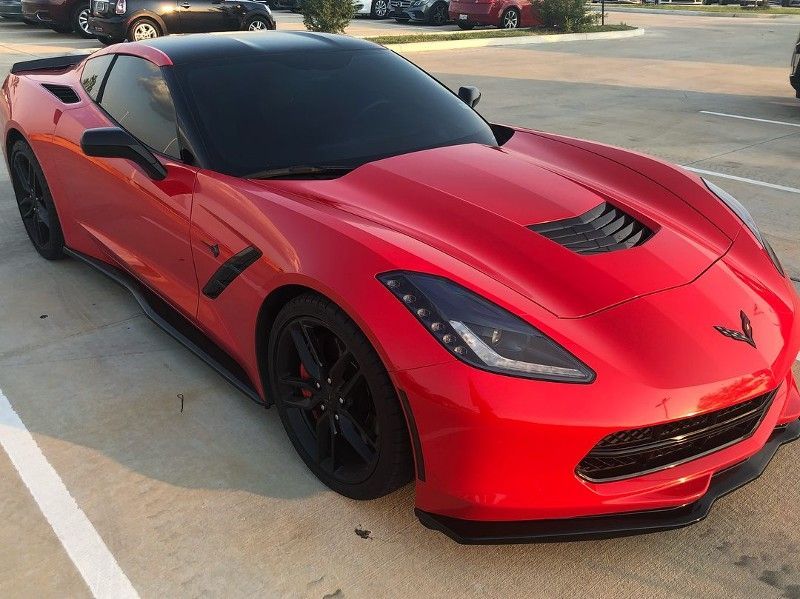 A red corvette is parked in a parking lot