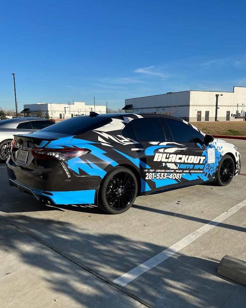 A black and blue car is parked in a parking lot.