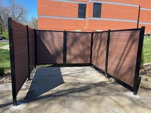 A wooden vinyl fence is sitting in front of a brick building