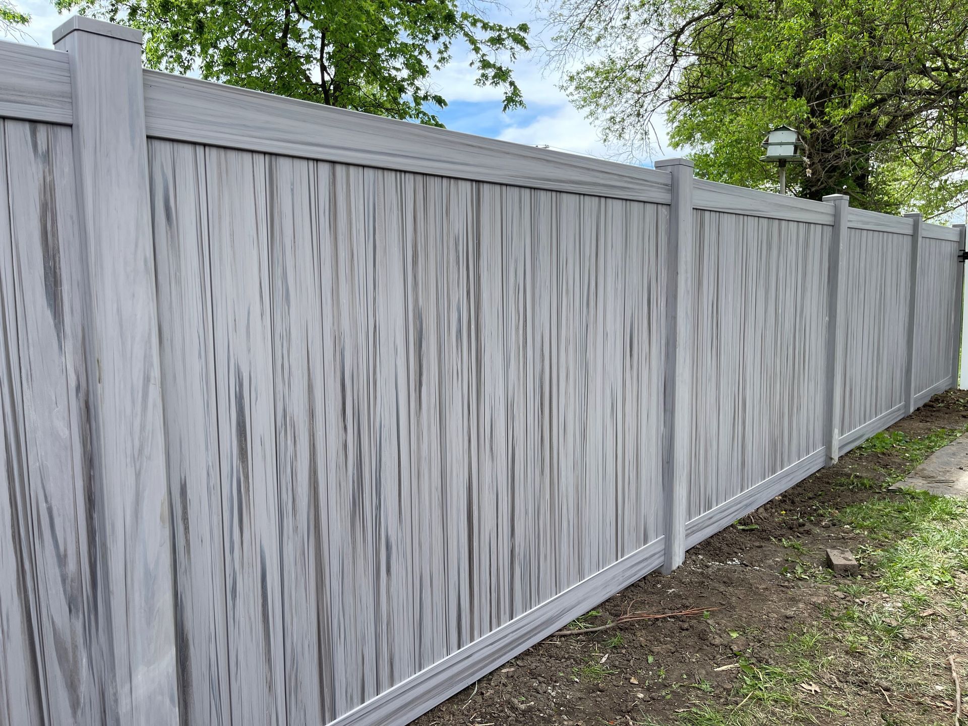 A white wooden fence is sitting in the grass in front of a house