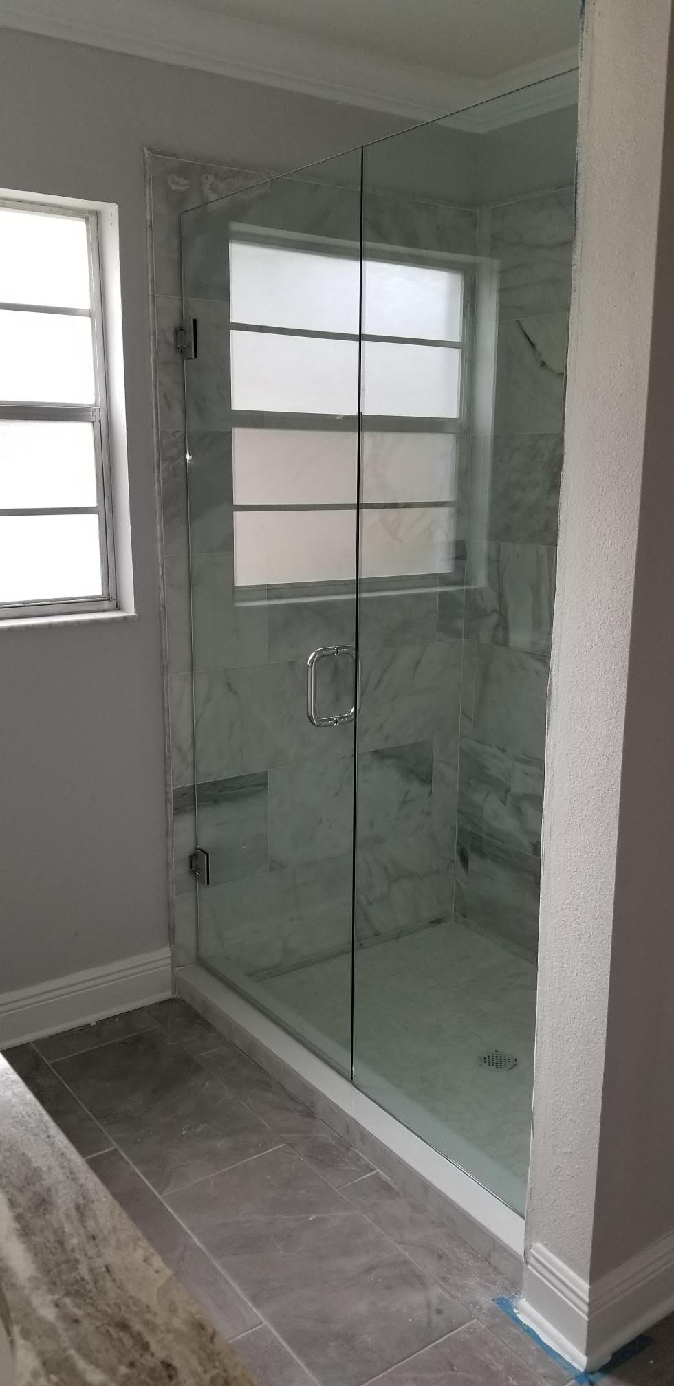 A bathroom with a walk-in shower and a window