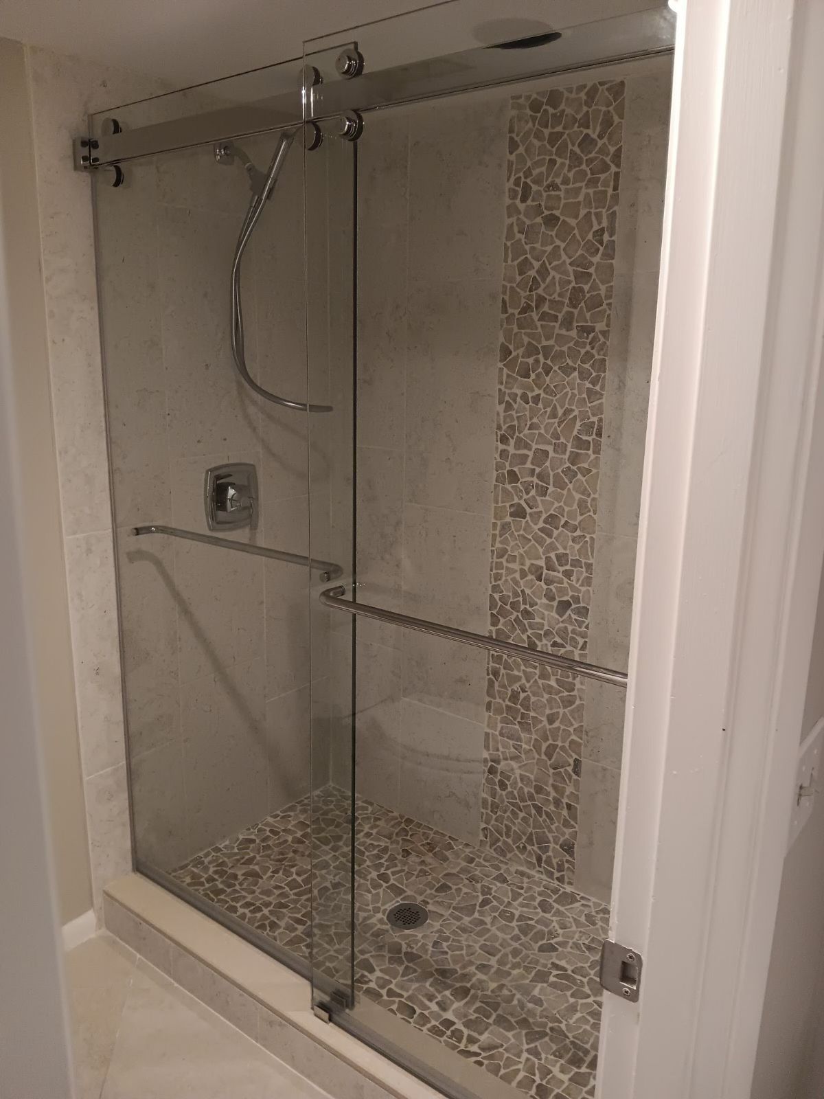 A bathroom with a sliding glass shower door and a tiled floor