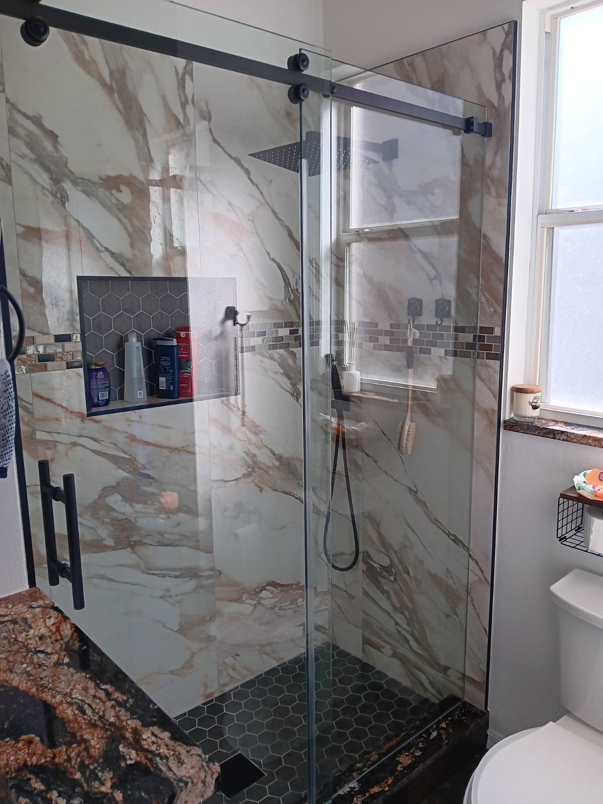 A bathroom with a sliding glass shower door and a toilet