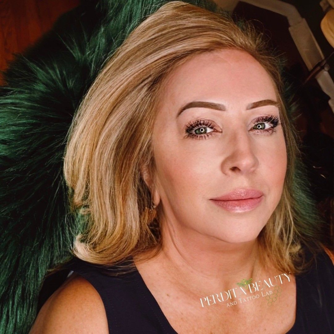 Blond woman with makeup, looking at the viewer, against a dark green furry background.