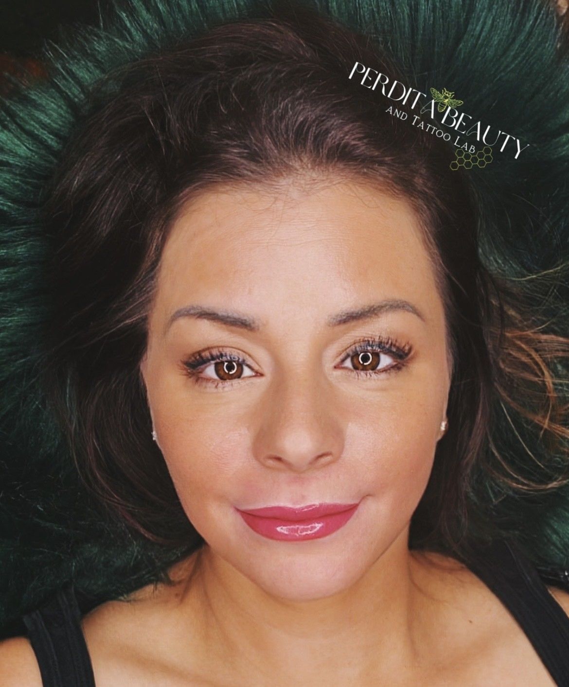 Woman with brown hair, makeup, smiling, on green fur.