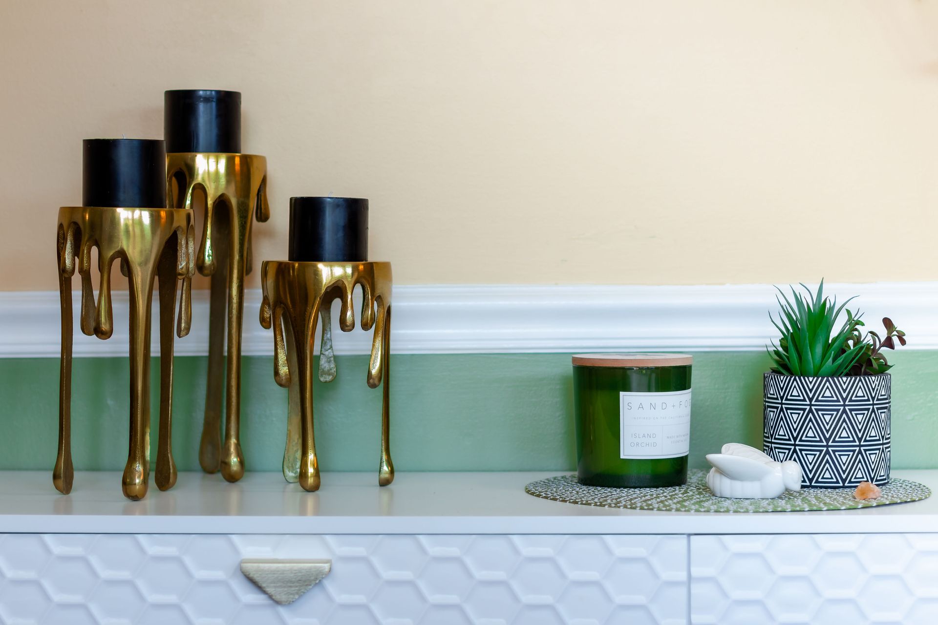 A white dresser with candles and a plant on it.