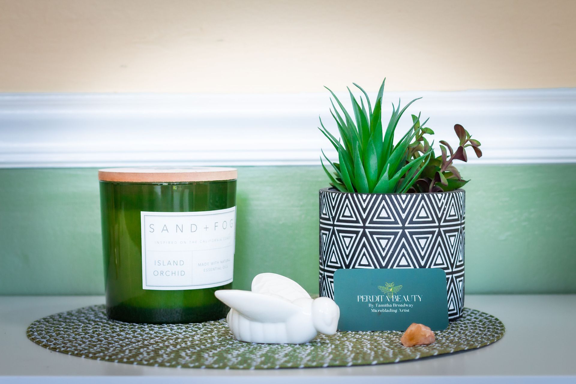 A green candle and a potted plant are on a table.