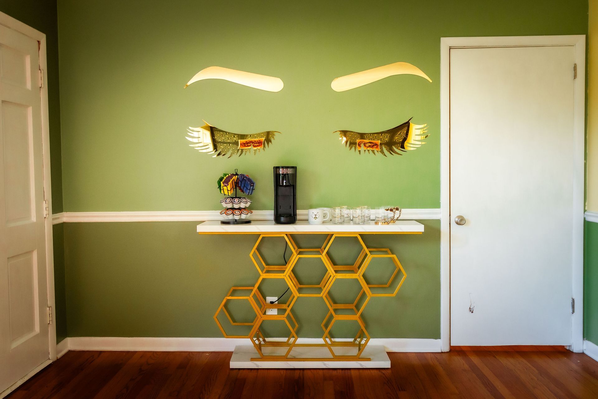 A room with a green wall and a table with a picture of a woman 's eyes on it.