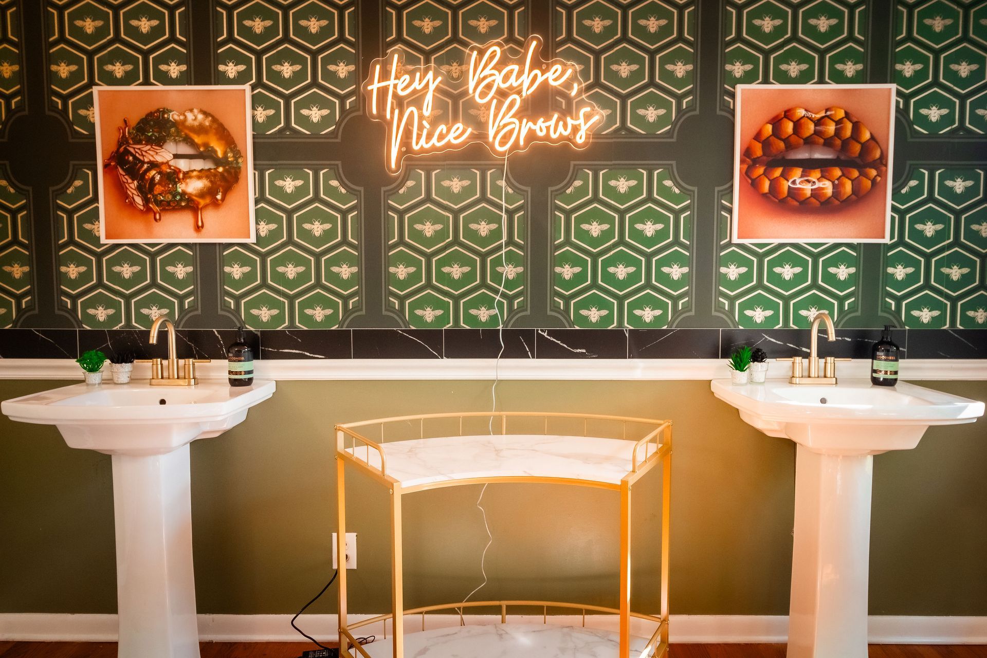 A bathroom with two sinks and a neon sign on the wall.