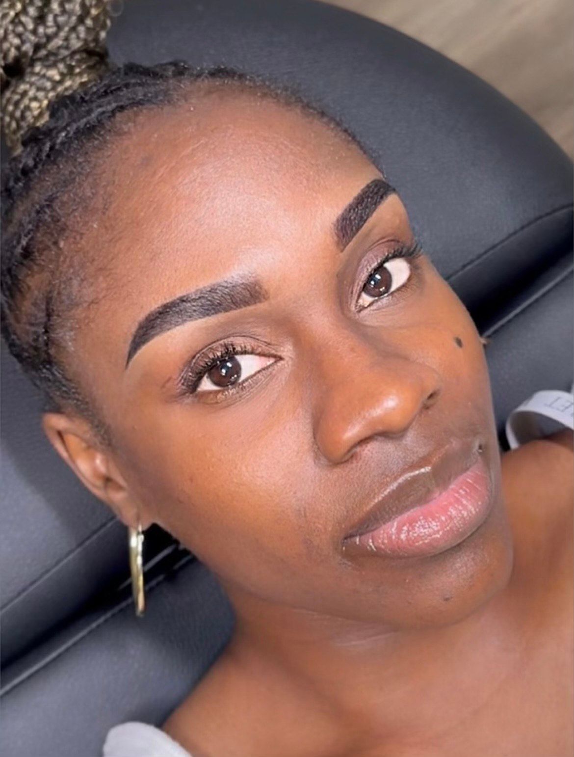 A close up of a woman's face with a bun and earrings