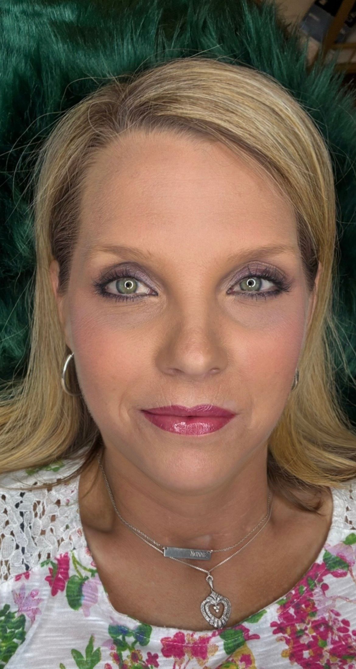 A close-up of a woman's face wearing a necklace and earrings.
