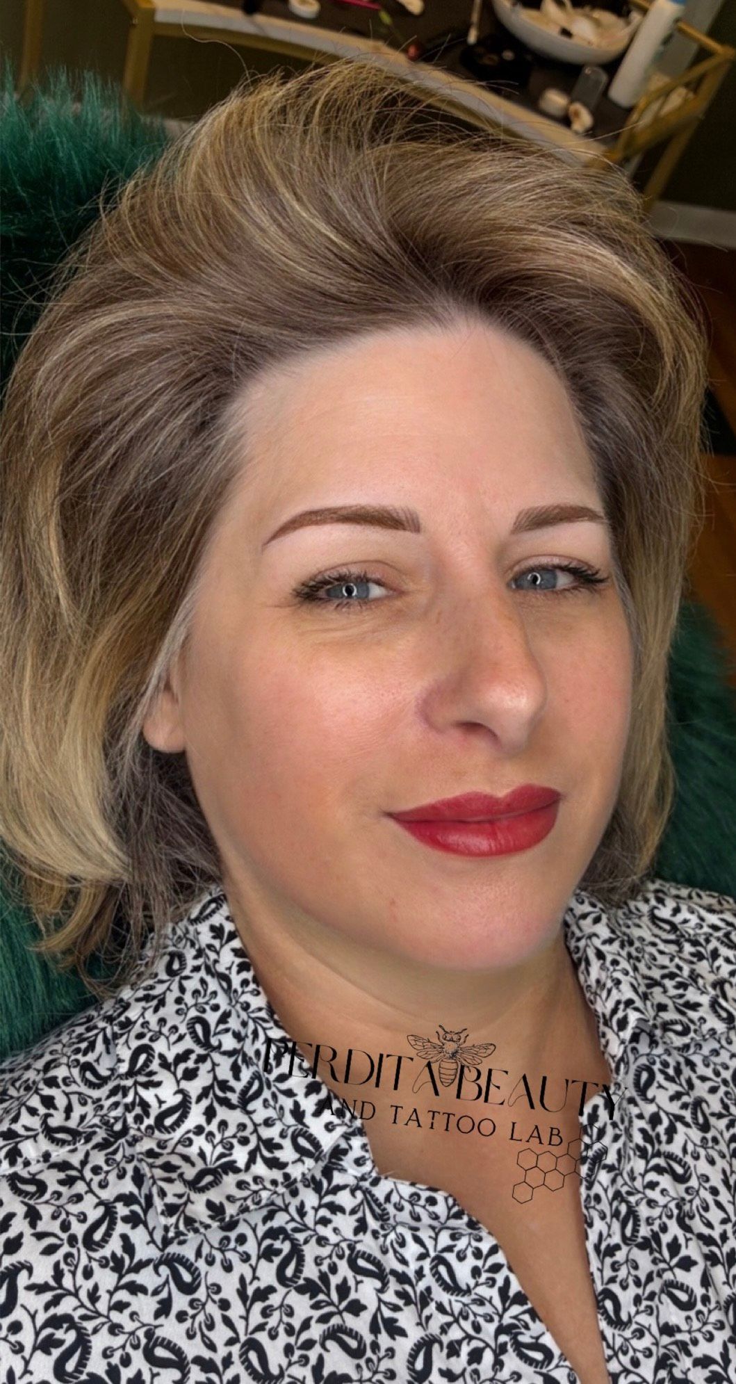 A woman with blonde hair and red lips is wearing a leopard print shirt.