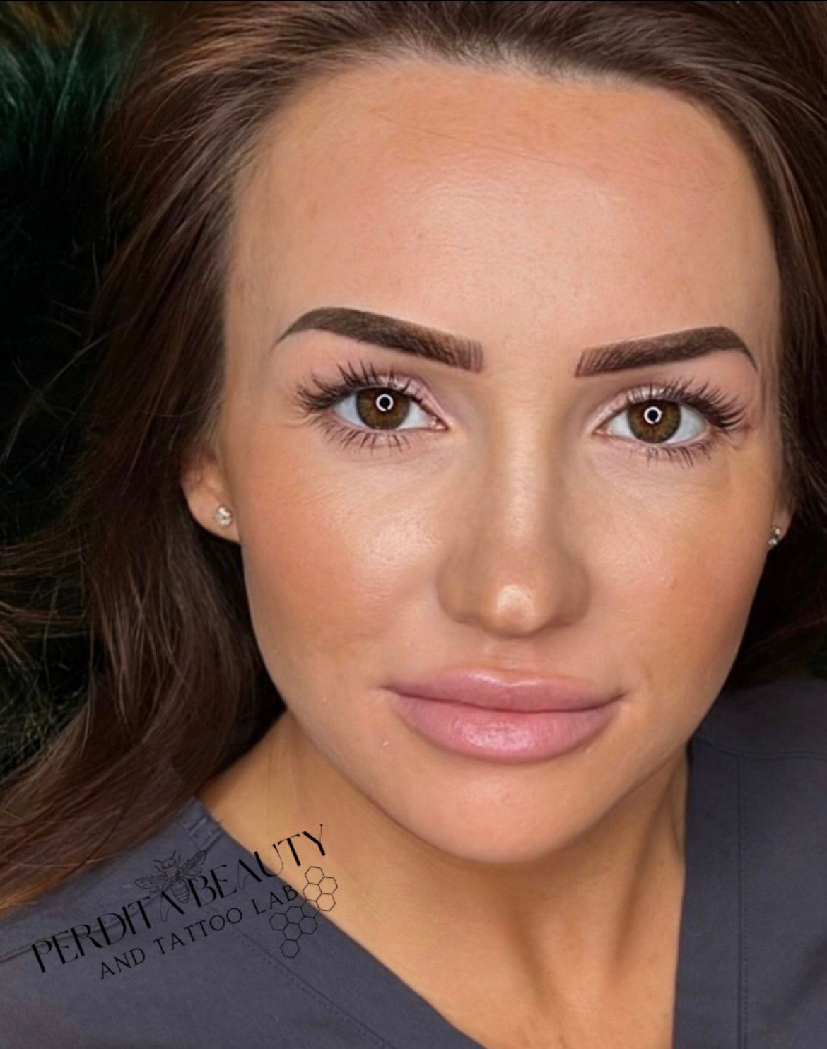 A close-up of a woman's face with a tattoo on her eyebrows