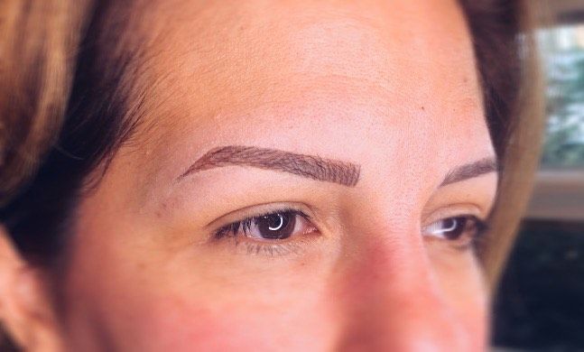 A close-up of a woman's face with a tattoo on her eyebrows.