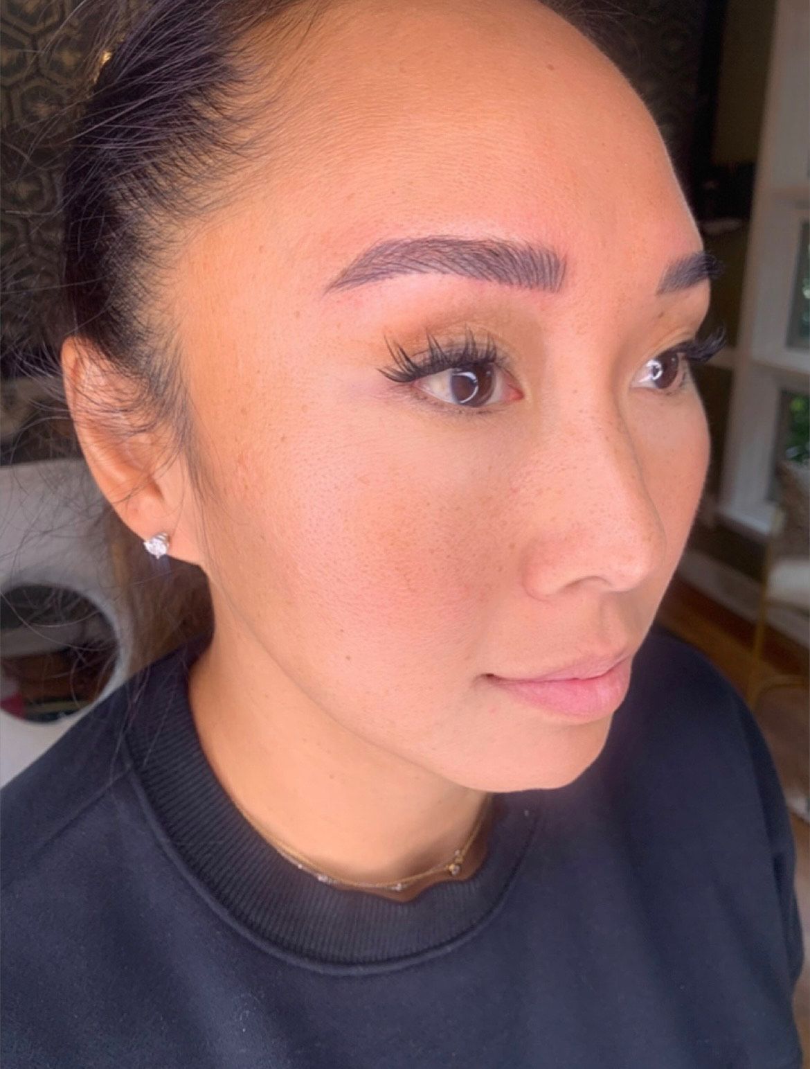 A close-up of a woman's face with a black shirt and earrings.