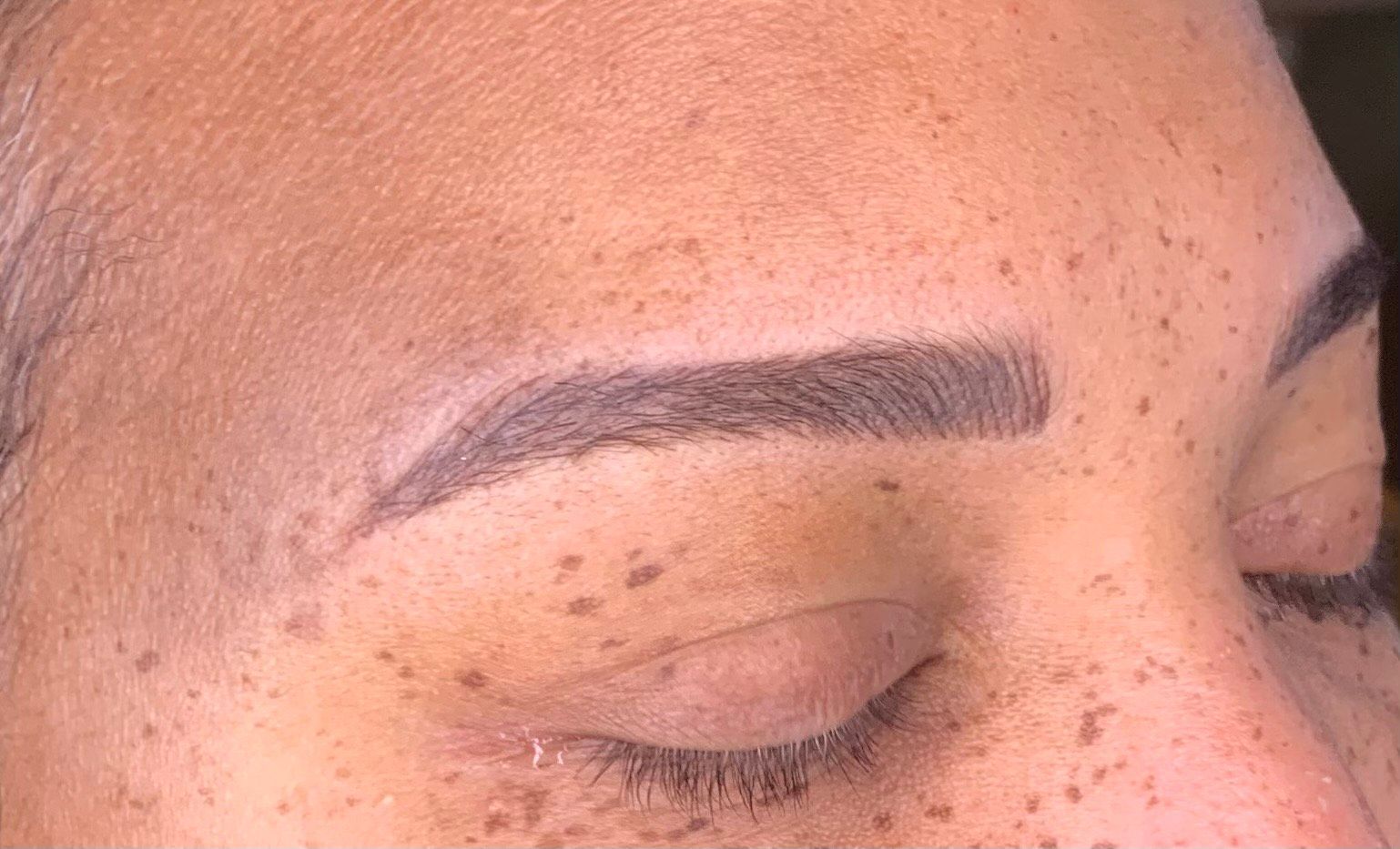 A close up of a woman's face with freckles and eyebrows.