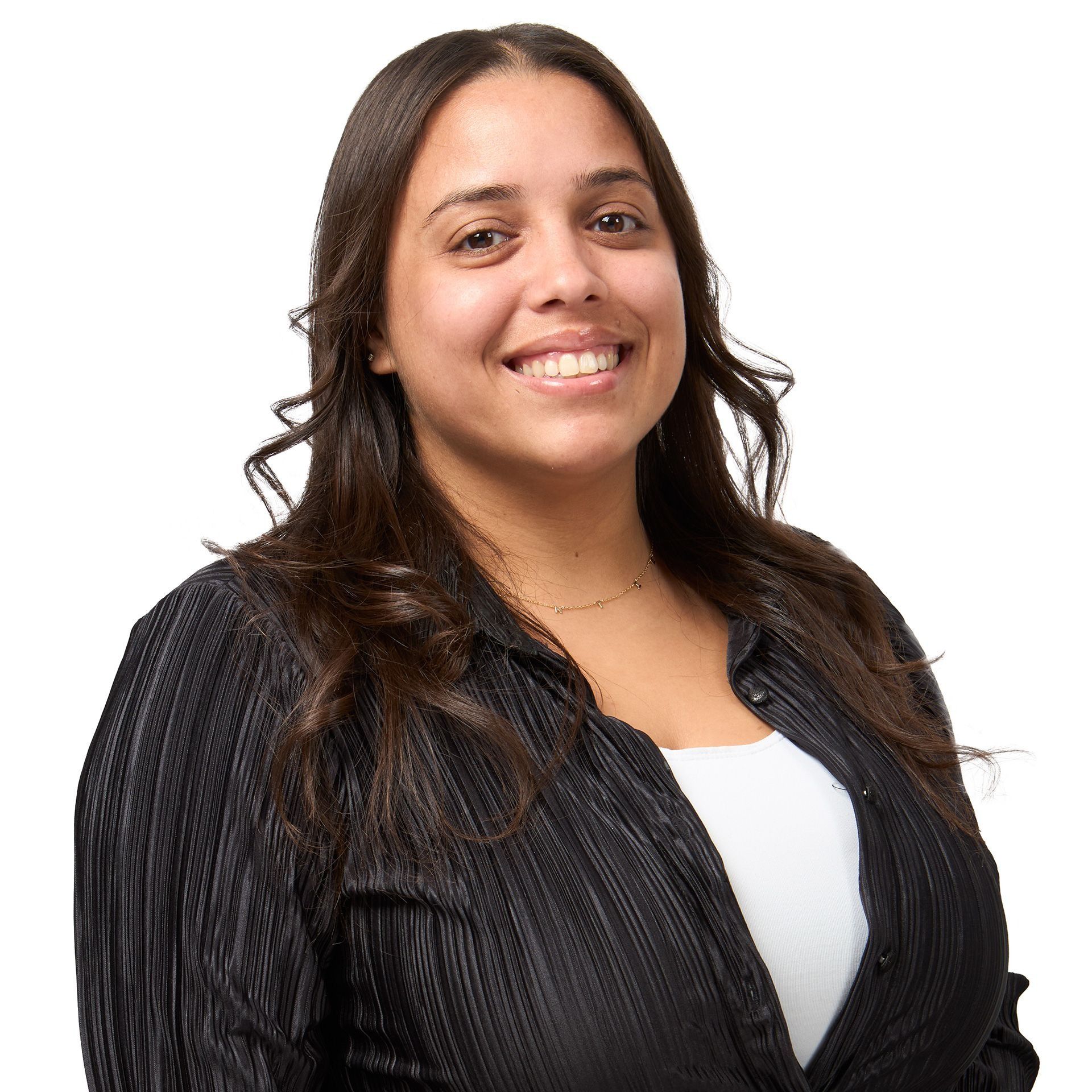 Woman with long brown hair, wearing a black blazer and white top, smiling at the camera against a white background.