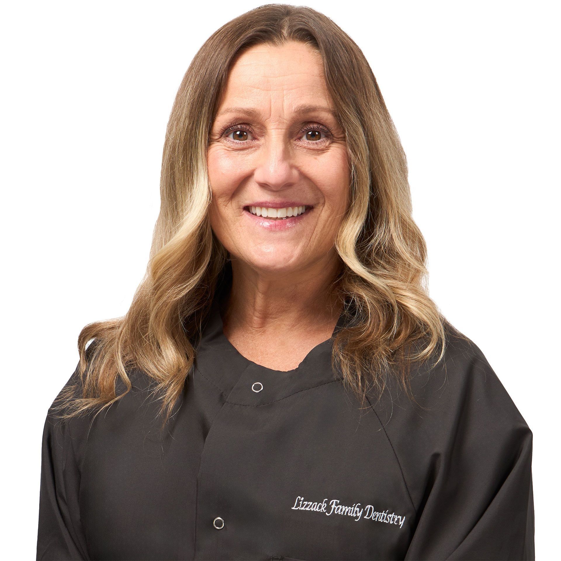 A woman with long brown hair and a friendly smile, wearing a black uniform with
