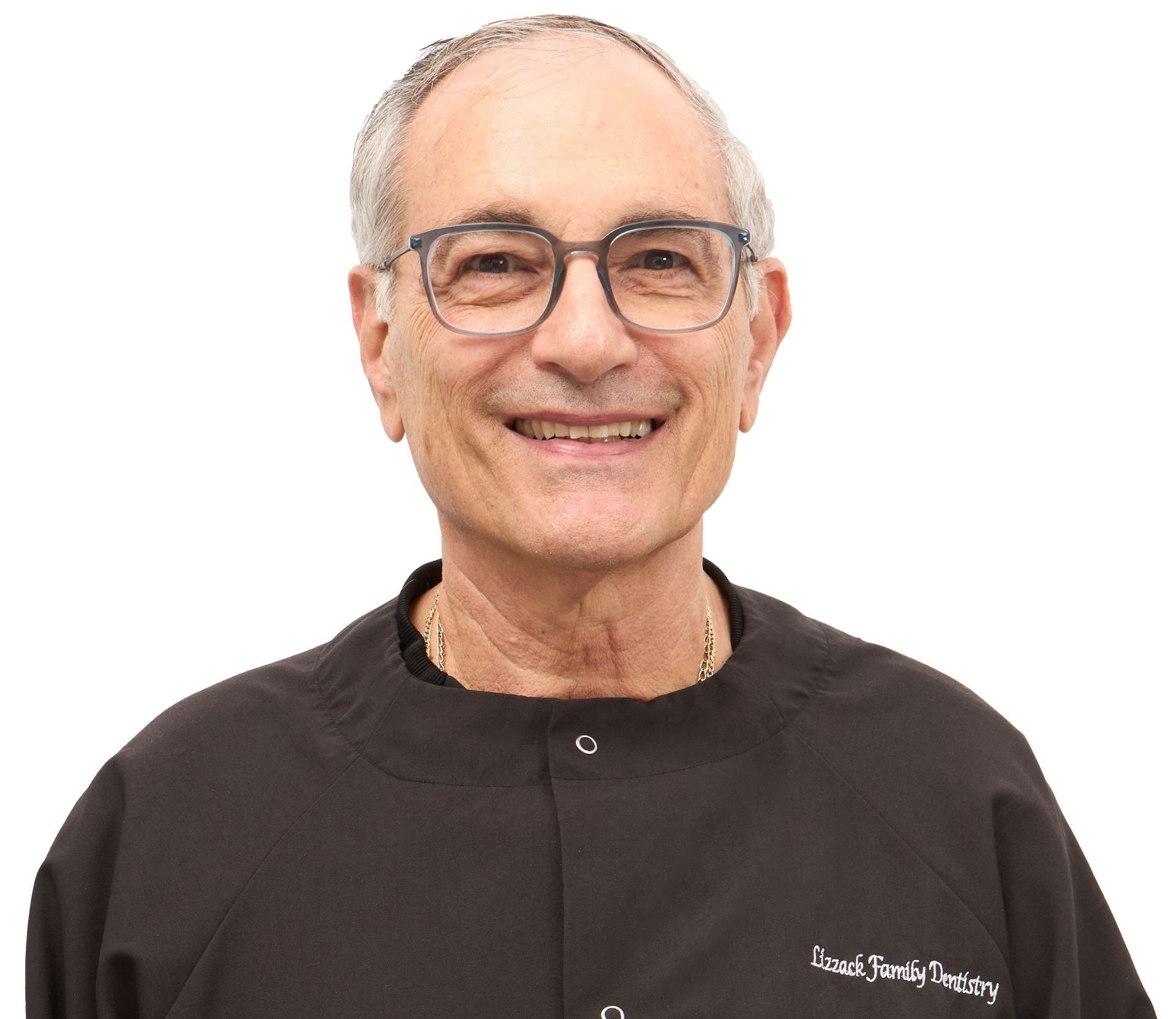 A smiling older man with glasses, wearing a black medical scrub top against a white background.