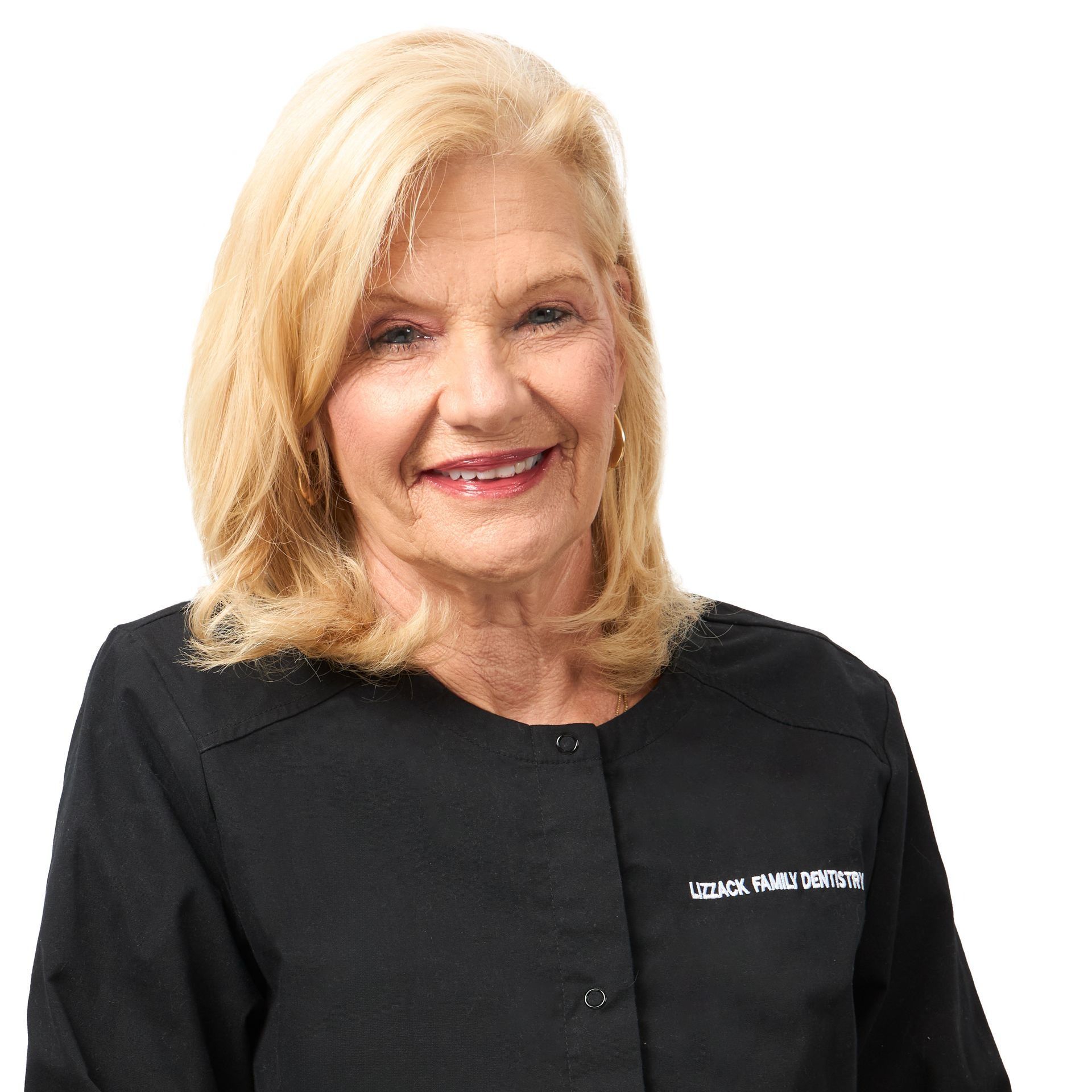 A smiling, older blonde woman wearing a black shirt with the words