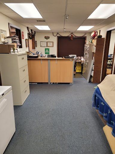 Office space with a blue carpet, beige cabinets, and a white filing cabinet.