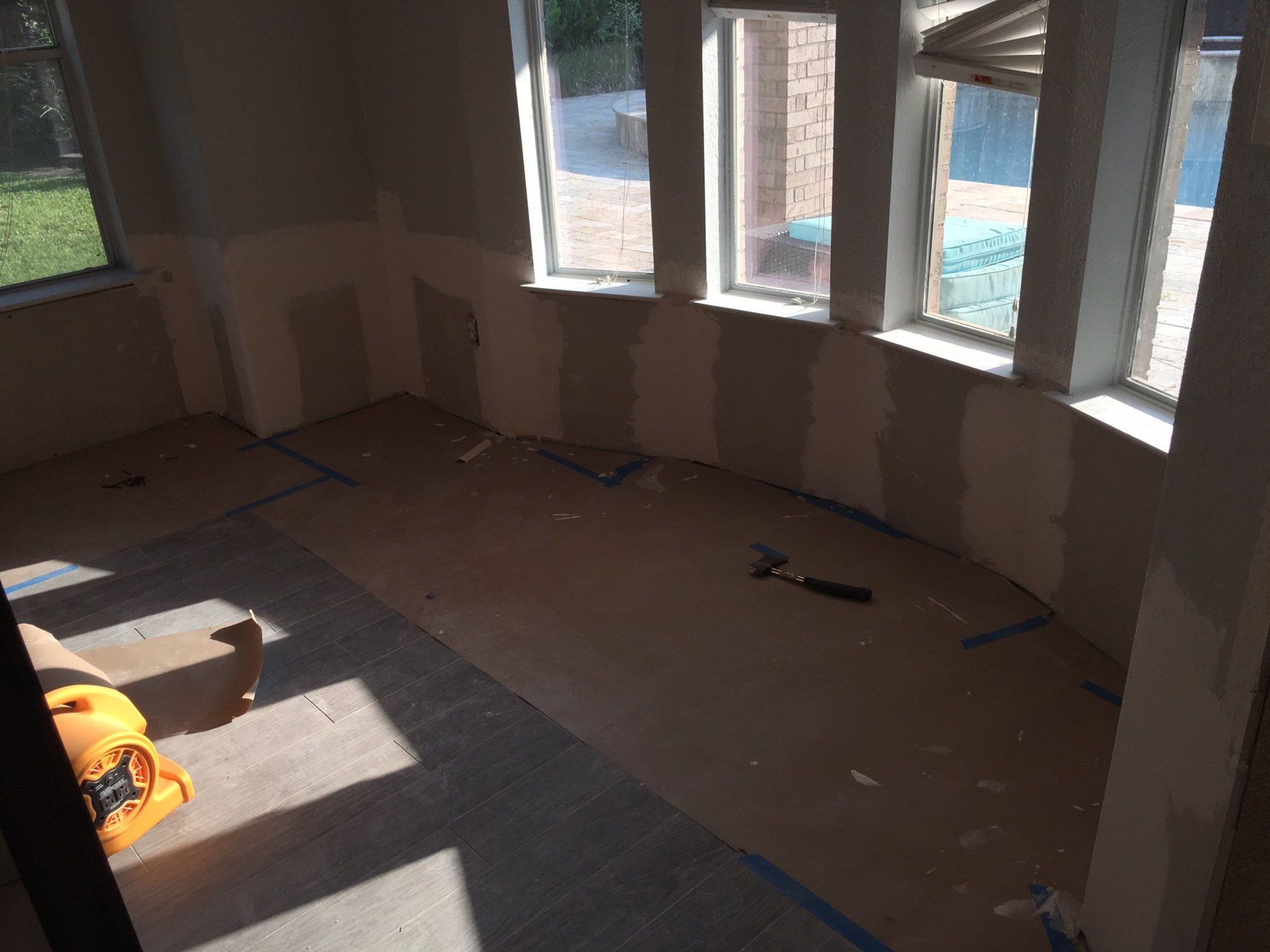 A room with a lot of windows and a hammer on the floor