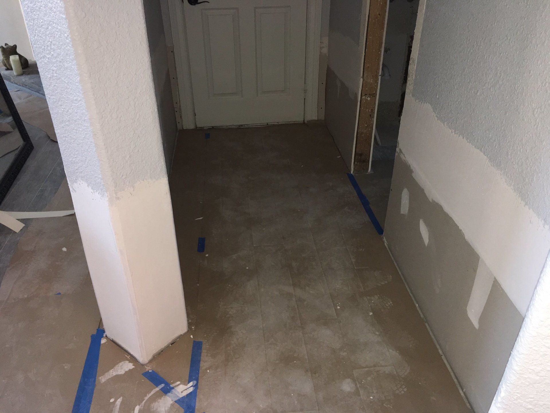 A hallway with a pillar and a door being painted