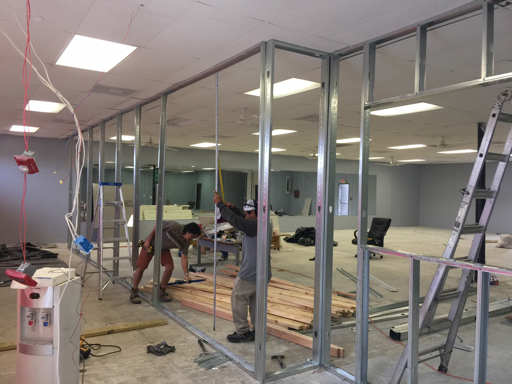 A couple of men are working on a wall in a room.