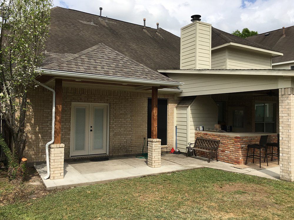 A brick house with a covered patio in the backyard.