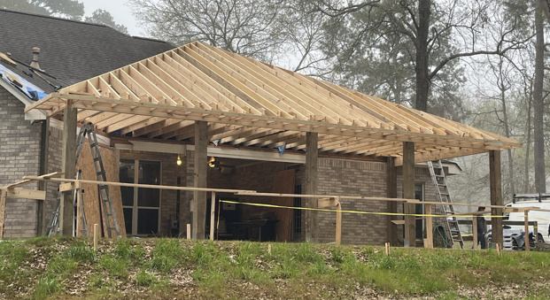 A wooden structure is being built on top of a brick building.