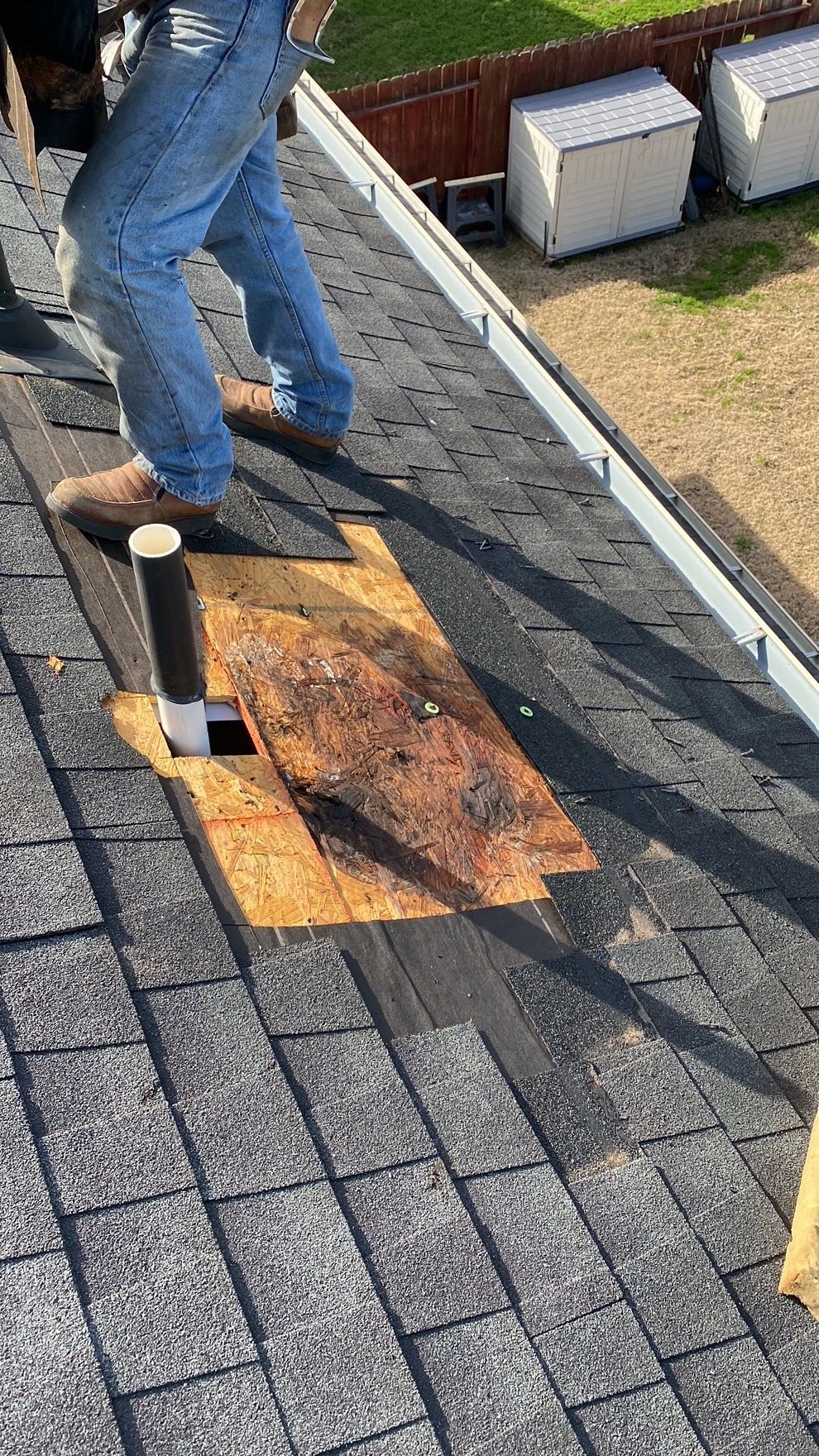 A person is standing on top of a roof with a hole in it.