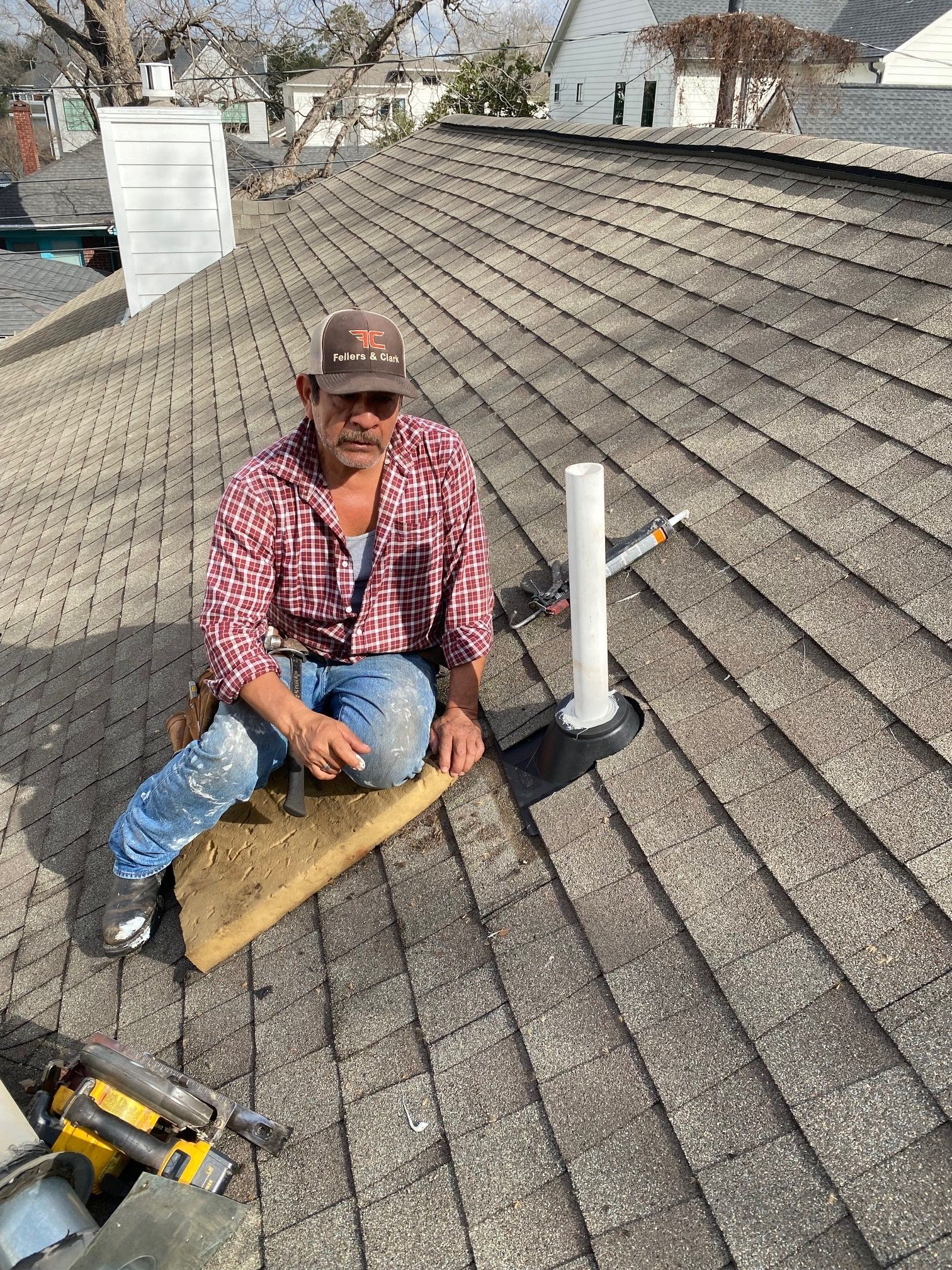 A man is kneeling on the roof of a house.