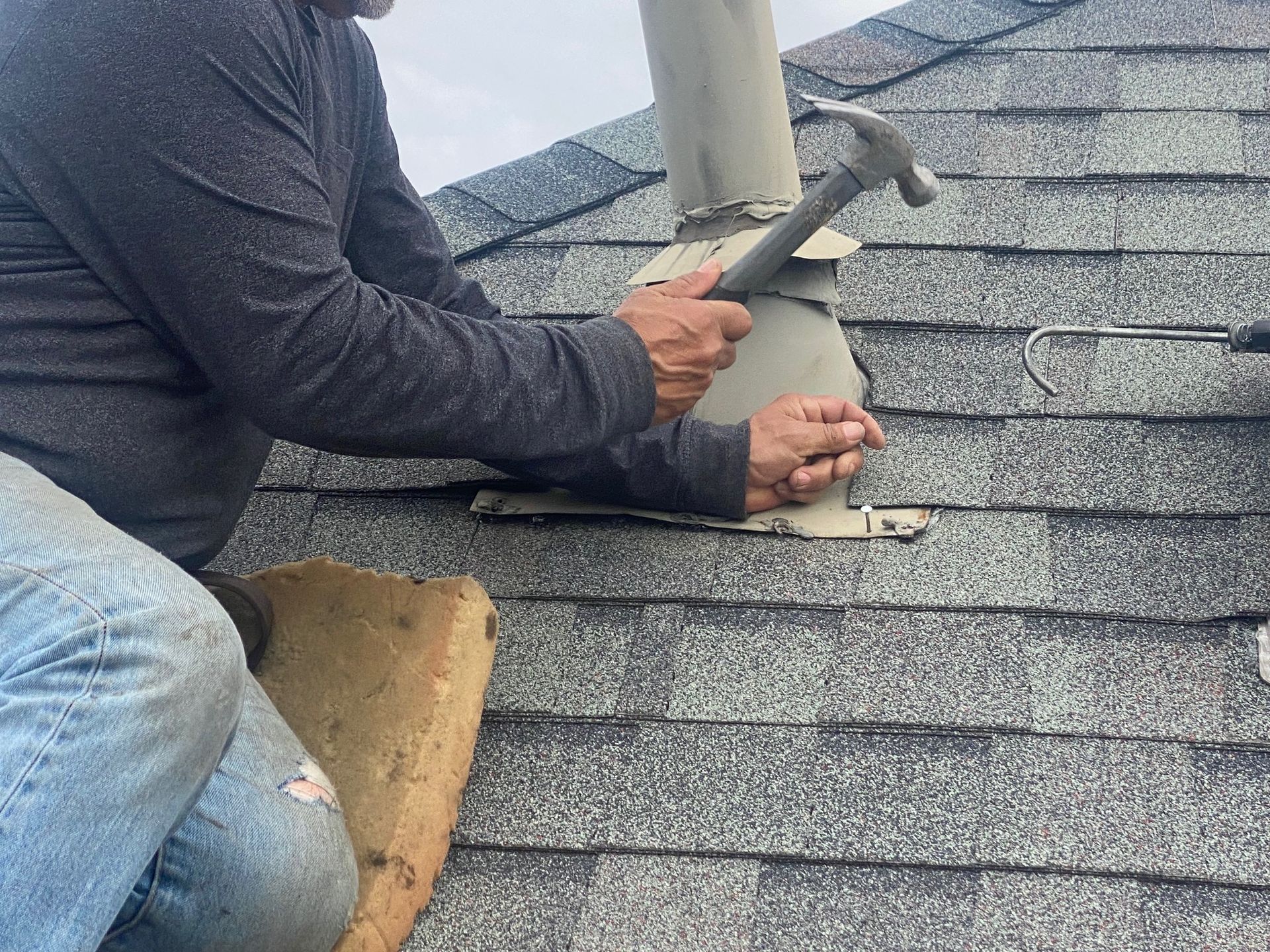 A man is working on a roof with a hammer.