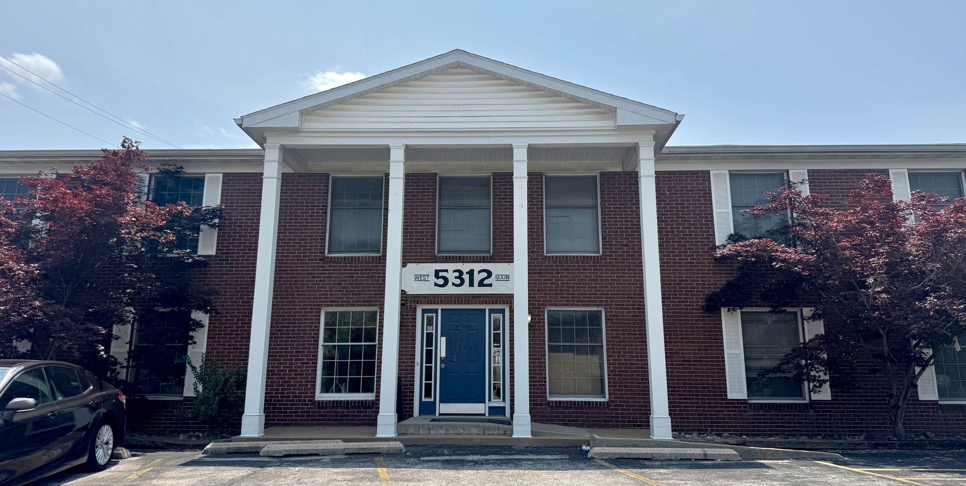 A large brick building with a blue door and a car parked in front of it.
