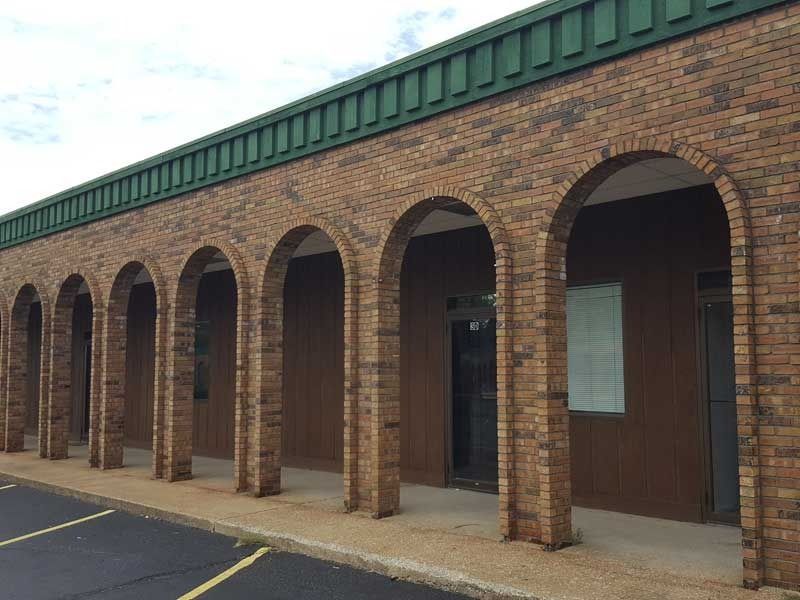 A brick building with arches and a green roof